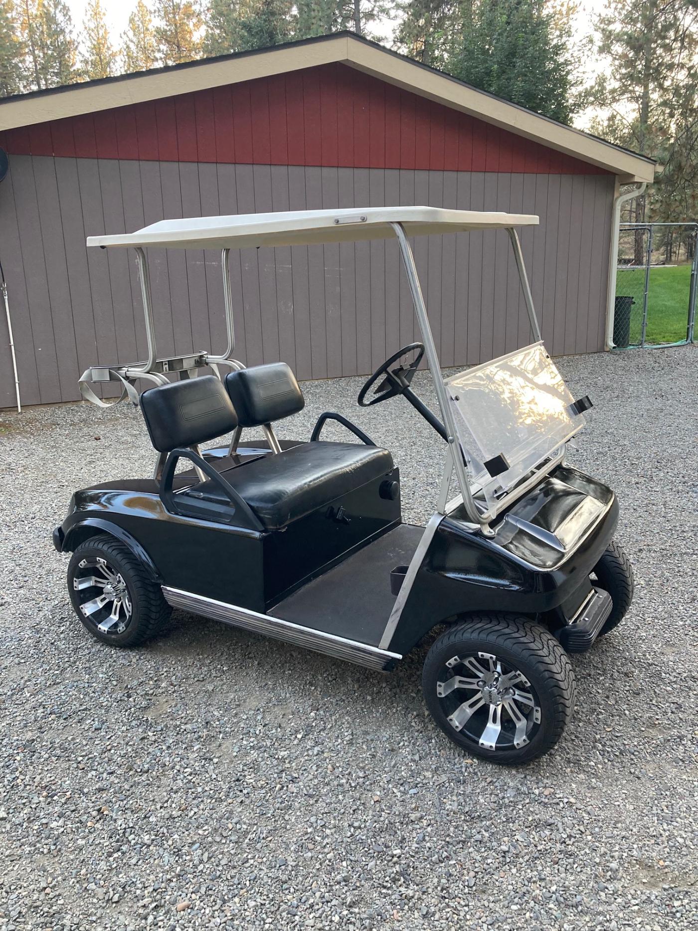 Rebuilt golf cart full view — black custom body with oversized off-road tires