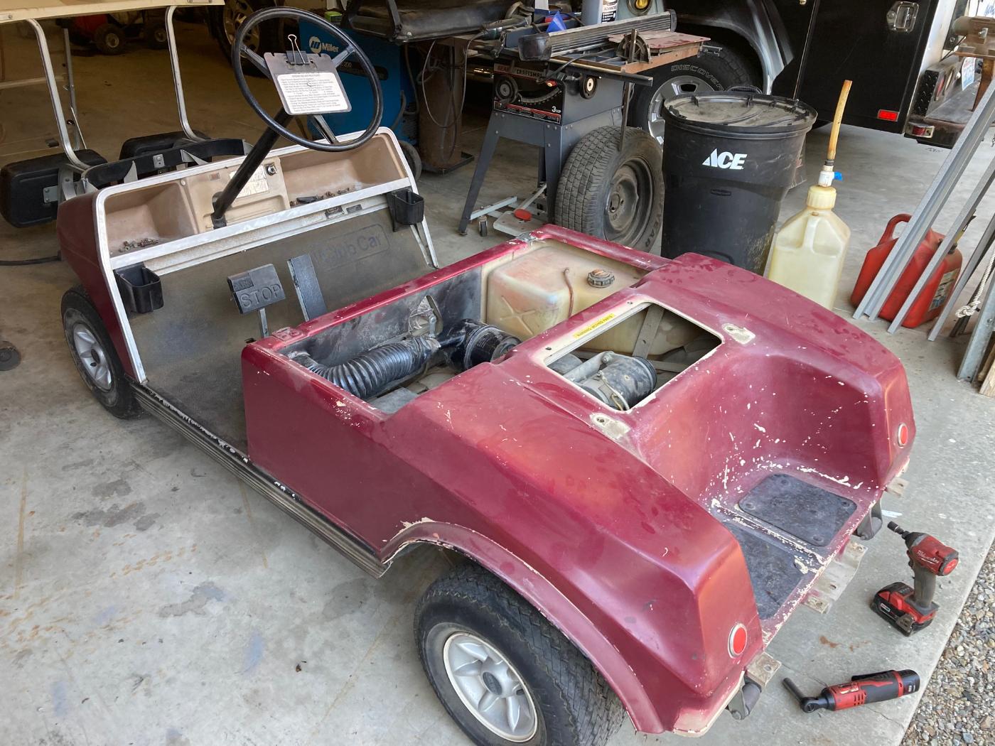 Golf cart before rebuild — faded maroon body stripped in shop