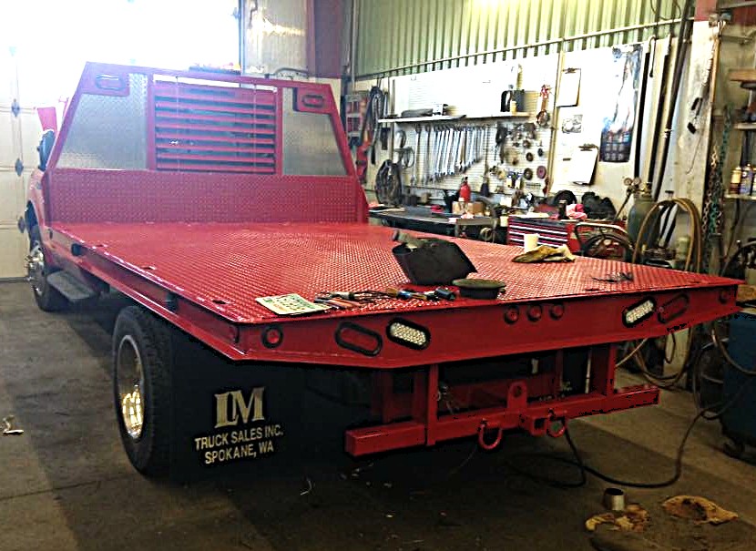Custom red steel flat bed fabricated and installed on a truck